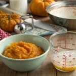 A bowl of fresh whipped heavy cream next to a can of pumpkin puree, highlighting the key ingredients.