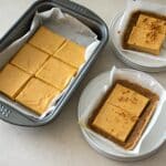 A perfect slice of no-bake pumpkin cheesecake with a creamy filling and a firm graham cracker crust, garnished with a dollop of whipped cream and a sprinkle of cinnamon."