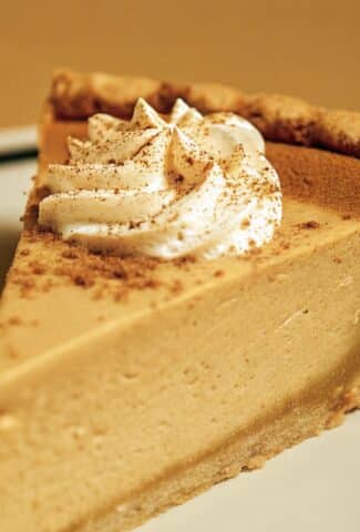 A classic pumpkin pie baked in a crust, showing a smooth, deeply-colored filling and a decorative fluted edge