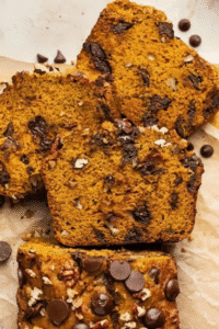 Sliced pumpkin bread with chocolate chips and nuts on parchment paper.