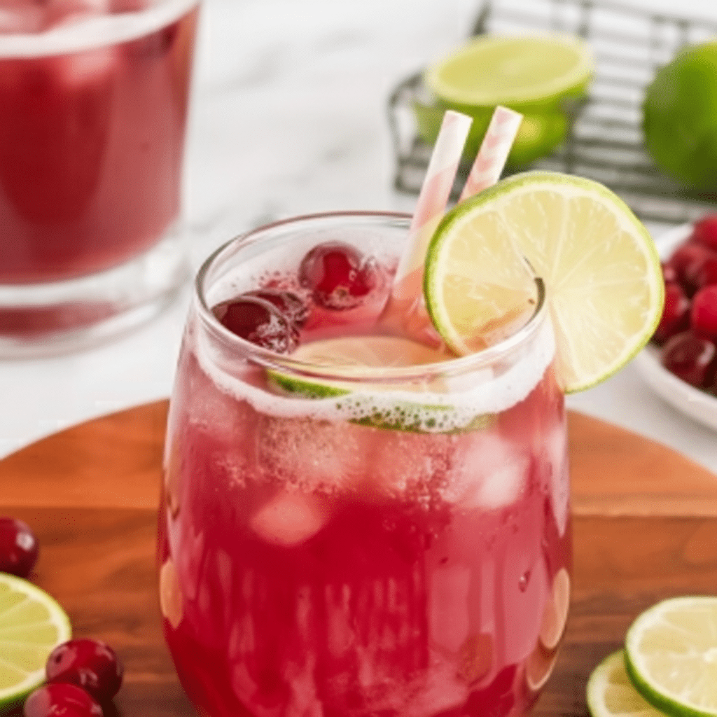 Sparkling Cranberry Pineapple Festive Punch in punch bowl with lime slices and cranberries.